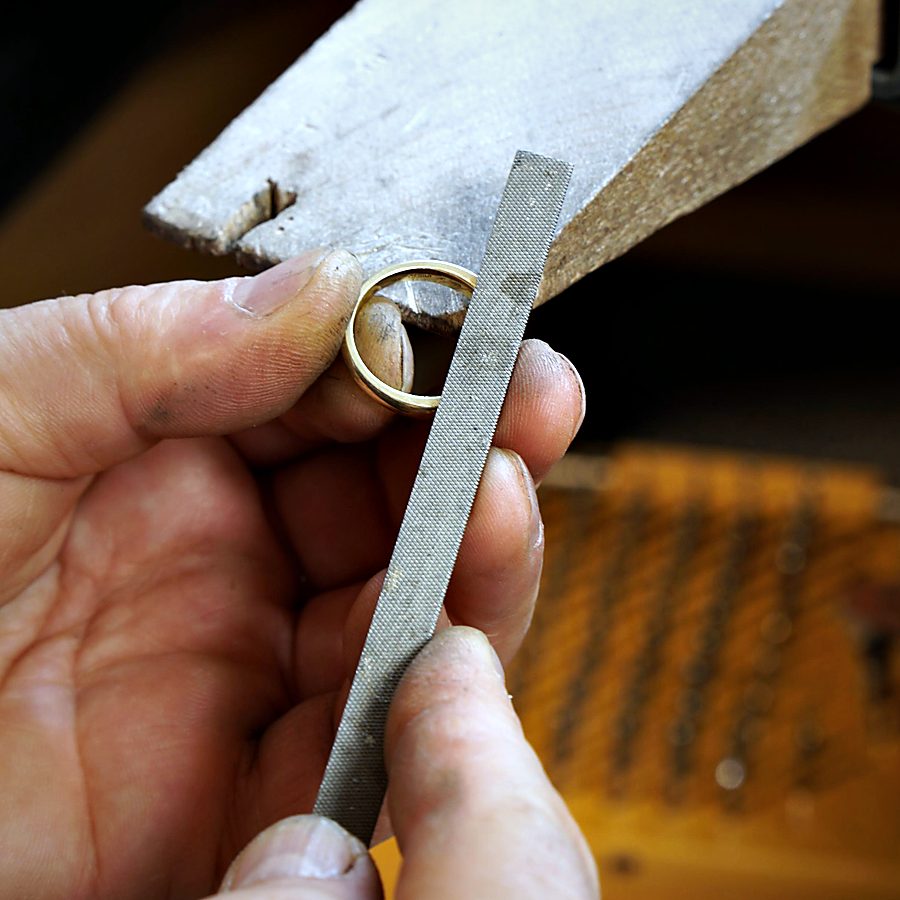 Ein Goldring wird am Feilnagel von Hand gefeilt