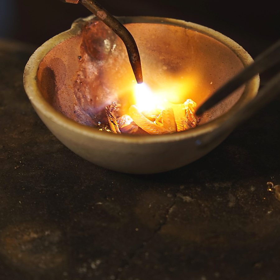 Gold glüht im Tiegel unter der Flamme